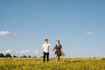 Happy love couple holding hands together and looking at each other on horizon on sunny day, outdoors. Young caucasian heterosexual family romantic trip or walk in nature. Relationship, travel concept