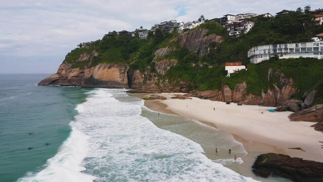 Aerial view of Praia da Joatinga, a paradise in Rio de Janeiro, Brazil. Sunny day with some clouds in the morning. Sea with good waves for surfers. Greenish sea. Drone take.