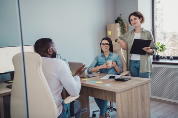 Photo of cheerful happy agents sitting table working discussing last news smiling indoors workplace workstation