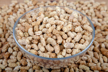 Dried white mulberry in glass bowl on wooden background