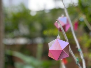 Pink Handmade Christmas Trapezoid hanging on a tree branch.