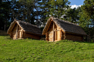 Fototapeta na wymiar Historic Slavic dwelling on the Molpir hill in the Little Carpathians. Two wooden cottages with straw roof on the hillfort.