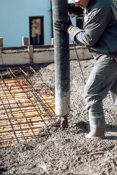 Concrete automatic pump tube working on construction site, workers directing and pouring concrete. Portrait of worker