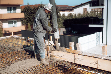 Industrial worker laying concrete with automatic tube pump. Workman on site with mortar and construction activities