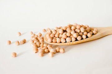 uncooked chickpeas in wooden spoon on white background