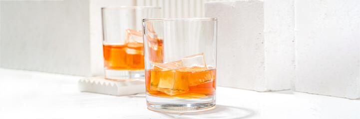 Alcoholic drink, cold summer hard strong alcohol cocktail, whiskey with ice in short glasses on white background