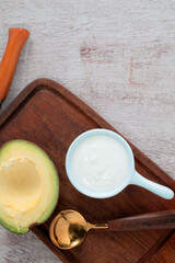 Healthy food yoghurt in bowl has avocado fruit on white wood table.