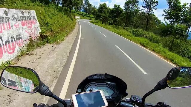 motorcycle ridding on tarmac road in green forest from rider angle