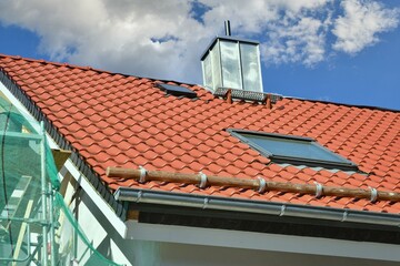 Modernes Ziegel- oder Metalldach mit Dachrinne, Dachfenster, Schneefang und Schornstein mit...