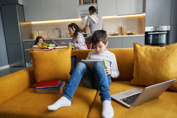 Focused boy writing homework in notepad on sofa