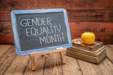 Gender Equality Month - white chalk handwriting on a slate blackboard with books, reminder of...