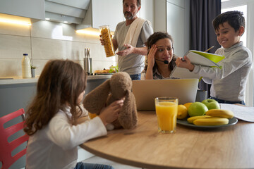 Woman working on laptop looking with terror on son homework