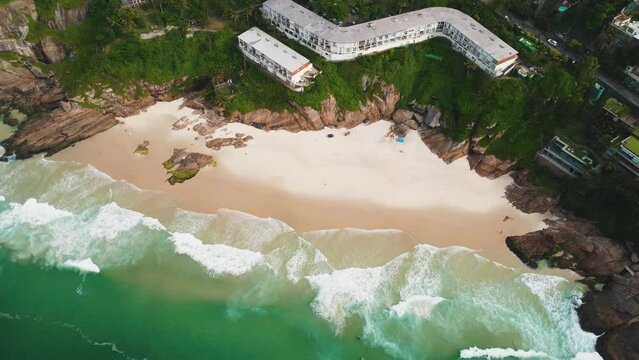 Aerial view of Praia da Joatinga, a paradise in Rio de Janeiro, Brazil. Sunny day with some clouds in the morning. Sea with good waves for surfers. Greenish sea. Drone take.