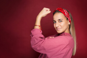 young woman with international women's day feminist gesture. isolated on red background.