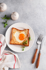 Breakfast on Valentines Day. Heart shaped egg with toast and microgreens on light grey background, breakfast table top. Valentines day breakfast. Top view. Mock up.