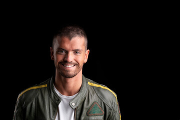 Young man looking at the camera smiling on a black background.