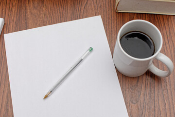 Desk with papers, books, pens and a cup of coffee on top.