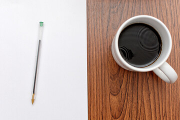 Desk with papers, books, pens and a cup of coffee on top.