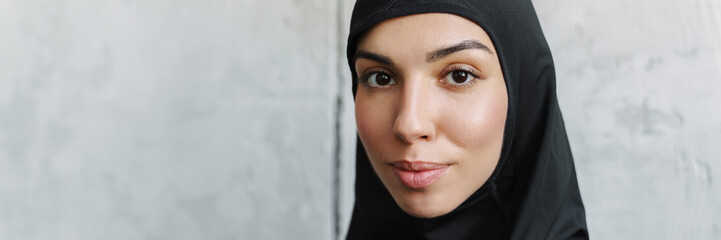 Young muslim woman in hijab posing and looking at camera indoors