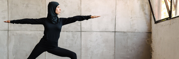 Young muslim woman in hijab doing exercise during yoga practice
