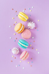 Tasty french macaroons on a violet pastel background.