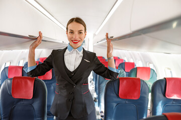 Cheerful stewardess standing in airplane passenger salon