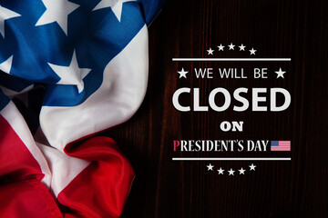 Obraz na płótnie Canvas President's Day Background Design. American flag on a wooden table with a message. We will be Closed on President's Day.