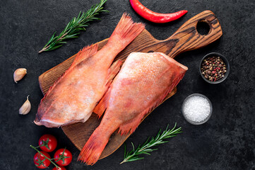 Raw red sea bass with rosemary and spices on stone background
