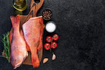 Raw red sea bass with rosemary and spices on stone background with copy space for your text