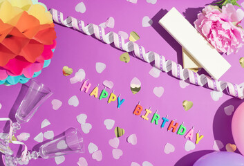 Colorful Happy Birthday candles and confetti on purple background,  top view. Festive or party background. Flat lay style. Birthday greeting card.