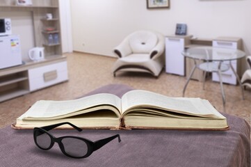 Reading book at home. Opened paper pages and spectacles at home