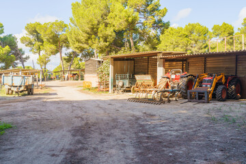 Several tractors and hay in a barn