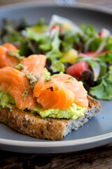 Detail of a delicious and light breakfast with Salmon on a bed of guacamole, bread and our delicious house salad.