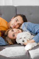 guy, girl, dog are lying on couch
