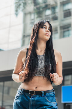 beautiful latin girl with brown skin waiting for public transportation in the city of Pereira-Colombia. young university student walking through the streets with a worried face.