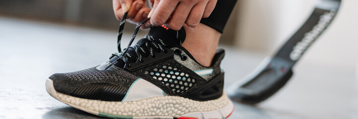 Young sportswoman with prosthesis tying her shoelaces