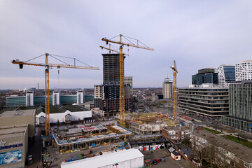 Fototapeta na wymiar Large cranes at construction site near central train station and commercial center of Dutch city. Real estate housing investment project. Aerial urban development cityscape.