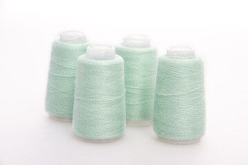 Green spool of thread isolated on white background. Skein of woolen threads. Yarn for knitting. Materials for sewing machine. Coil