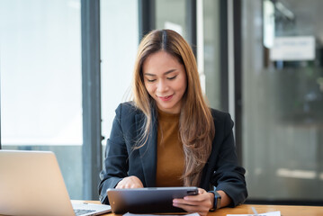 Asian businesswoman who is happy to work using a tablet.