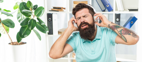 Businessman portrait singing along while listening to song in headphones in office, music