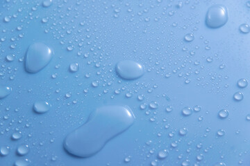Blue pastel water drops on light shiny surface