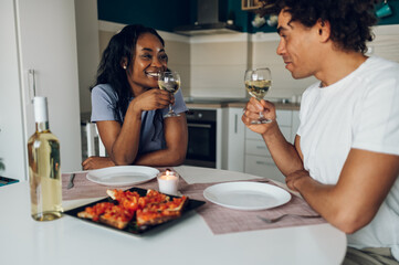 African american couple drinking white wine and having dinner at home