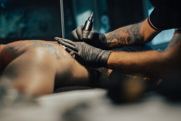 Tattoo artist holding a machine while working in a studio