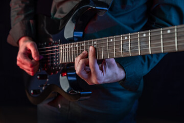 Fototapeta na wymiar Male hands playing electric guitar. Musician man with black guitar at a rock concert