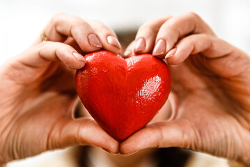 Red heart in women's hands close-up.