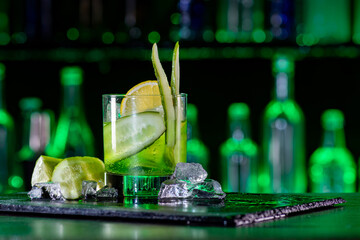 Cocktail with cucumber, ice on bar counter in a restaurant, pub. Fresh tonic drink with lime juice,...