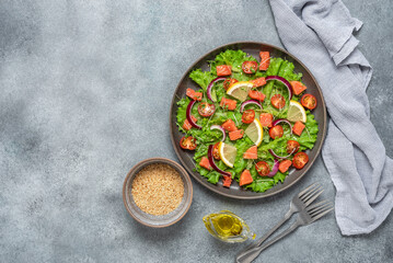Salad of fresh vegetables and salted salmon in a plate. Gray grunge background. Top view, flat lay.