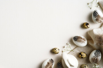 Happy Easter card design. Easter eggs decorated feathers with Easter rabbit, flowers on white table.
