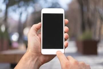 Human hand holding phone with blank screen and cityscape blur background