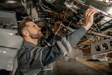 Bearded man maintenance technician checking airplane parts while working in repair station